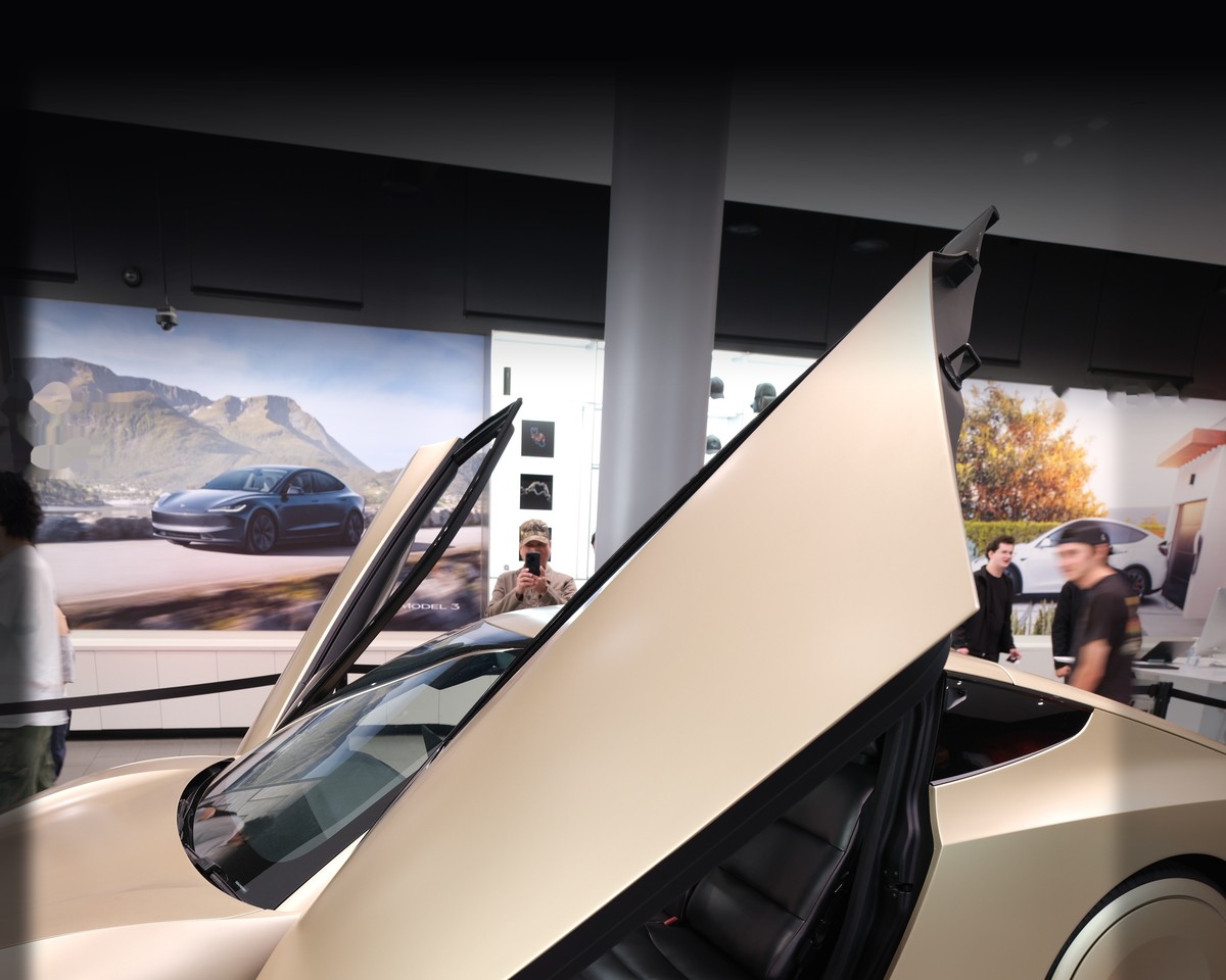 A Tesla Cybercab with an open falcon-wing door in a showroom