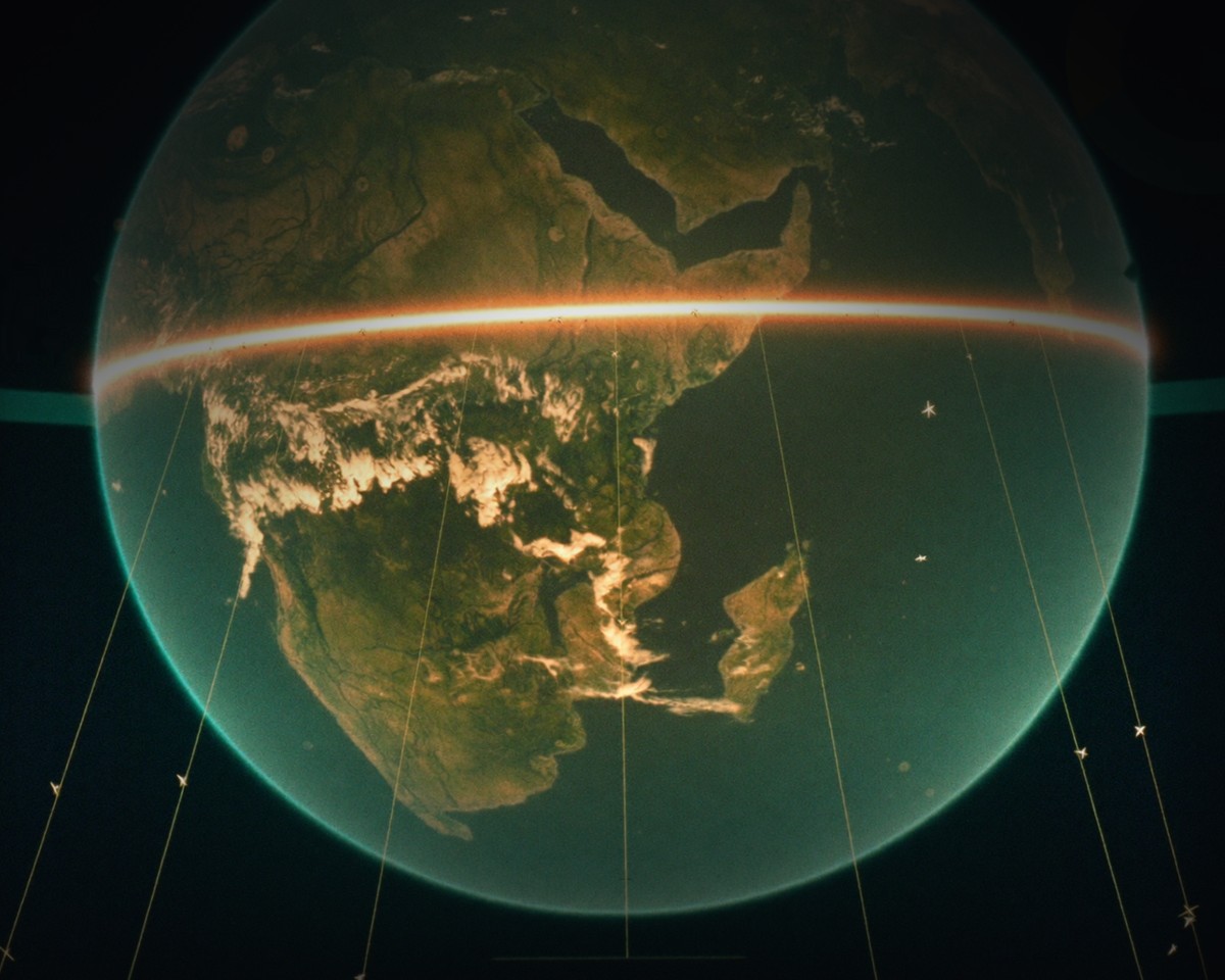 A glowing hologram of Earth above a control-room console